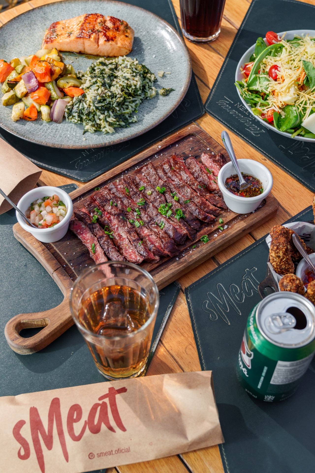 Tábua de carne fatiada com molhos e a sacola do Smeat